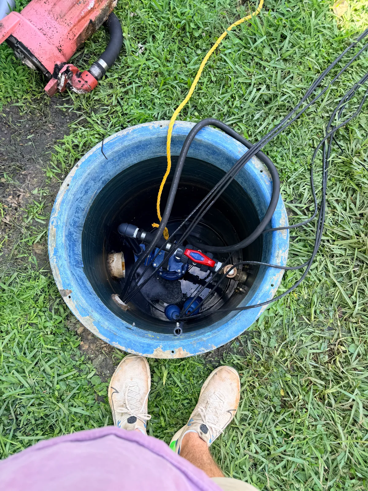 R&D plumber servicing a grinder pump station in the field, standing over the open basin